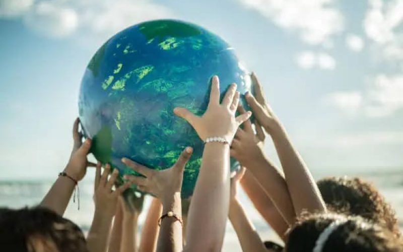 Close-up of children holding a planet at the beach